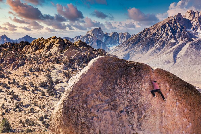 Man rock climbs on huge granite boulder in the Buttermilk area of Bishop, California with the Sierra Nevada behind Critique de ‘Accoster à la Vie’ par Gabriel Tallent