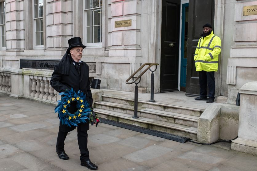 A man wearing an undertaker's attire, holding an 'EU' wreath, walks past the Cabinet Office on Whitehall. Réflexion sur la Relation Future Entre l’Union Européenne et le Royaume-Uni