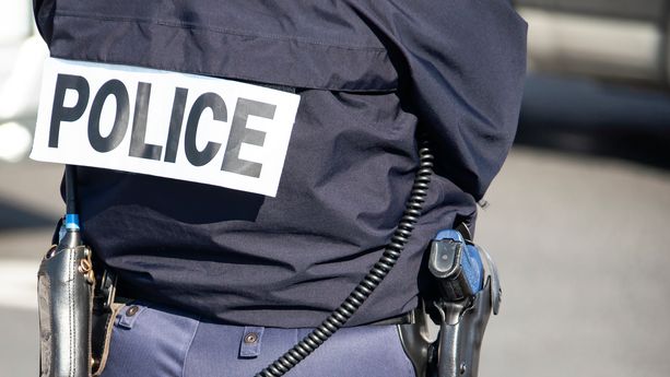 The back of the police officer with the inscription "POLICE" with a gun and a walkie-talkie. Un adolescent arrêté après le meurtre d’une octogénaire au Grau-du-Roi