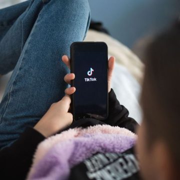 Nizhny Novgorod, Russia - October 03 2020: child with phone in his hands is lying at home on bed. Social Media tiktok is loaded on screen Nouvelles mesures pour limiter l’accès des jeunes aux réseaux sociaux